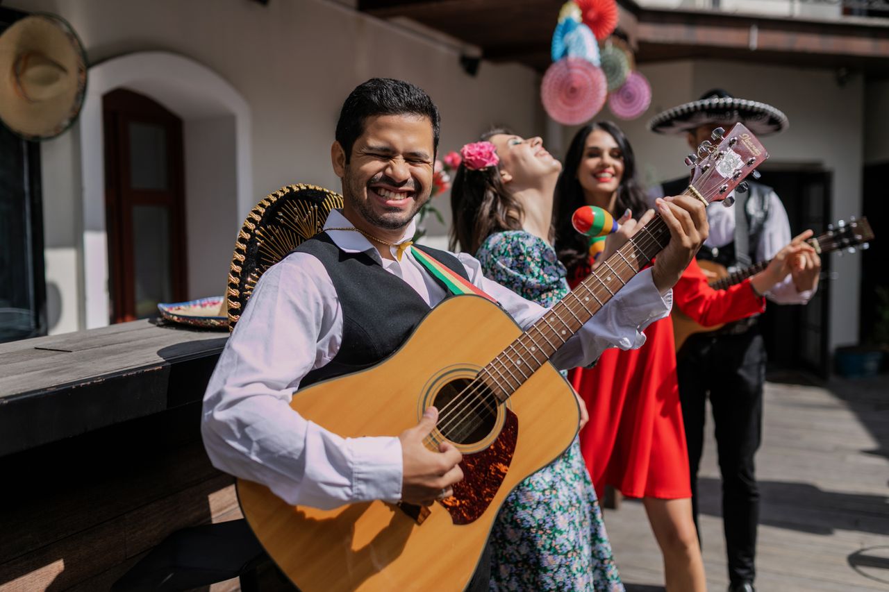 Joyful Mexican band playing guitars and maracas at a festive celebration outdoors, embracing vibrant culture.