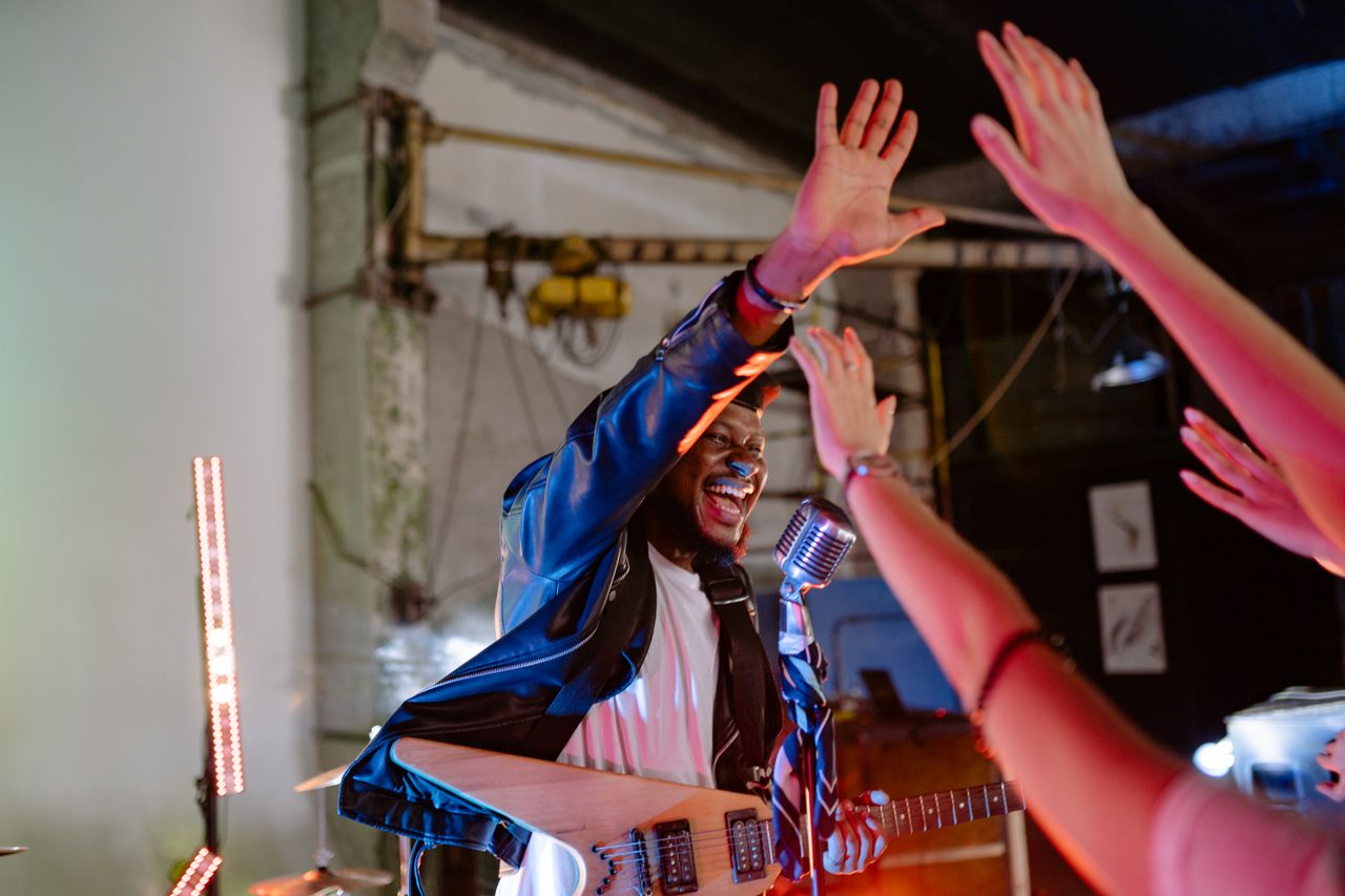 A lively indoor concert scene with a guitarist engaging the audience.